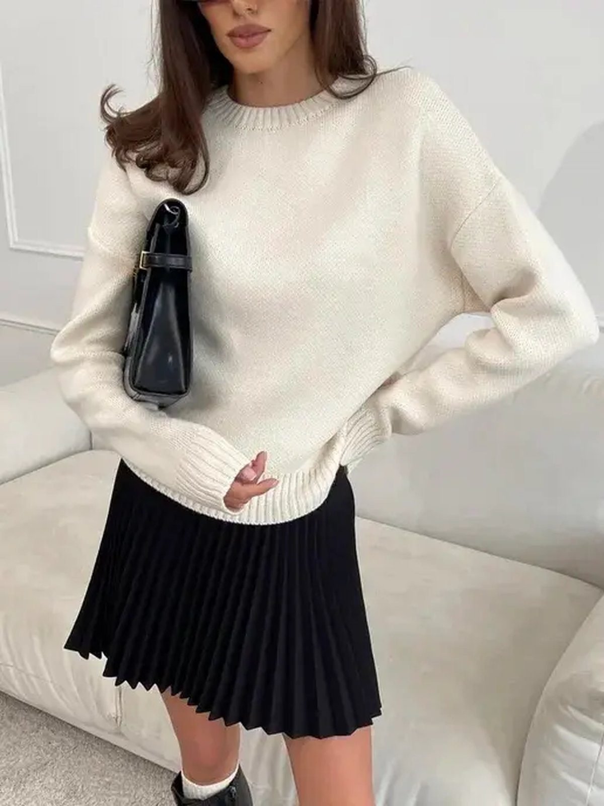 Woman wearing a pleated tennis skirt with an oversized fall sweater