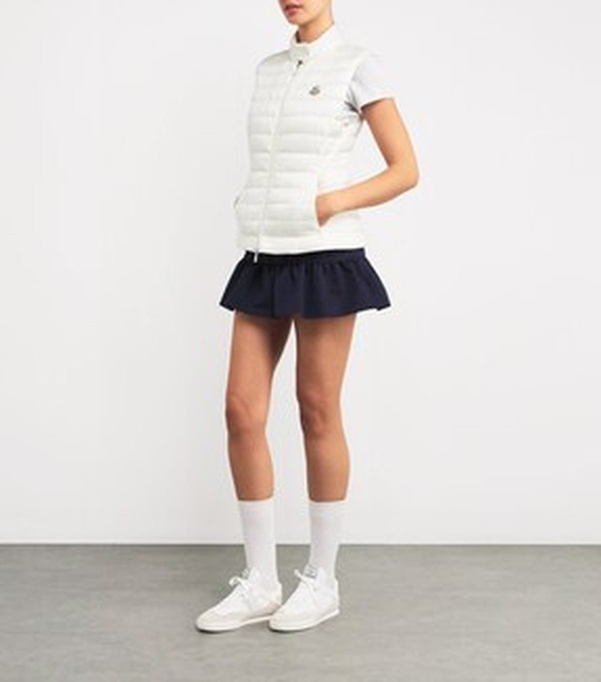 Woman wearing a tennis skirt with a puffer vest in autumn