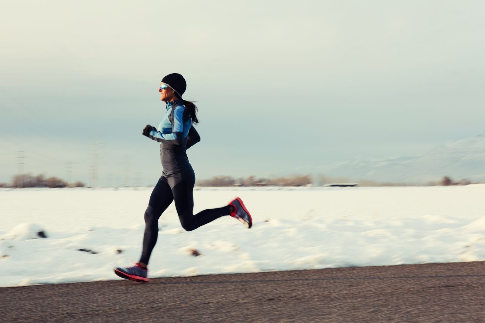 Woman running outdoors in a thermal base layer and leggings on a cold day