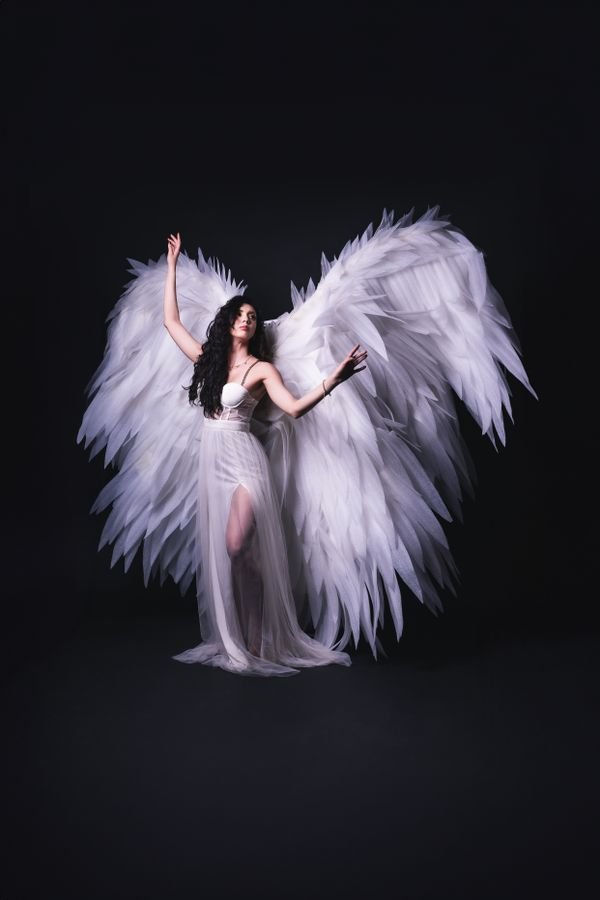 Woman in a guardian angel Halloween costume with large white wings
